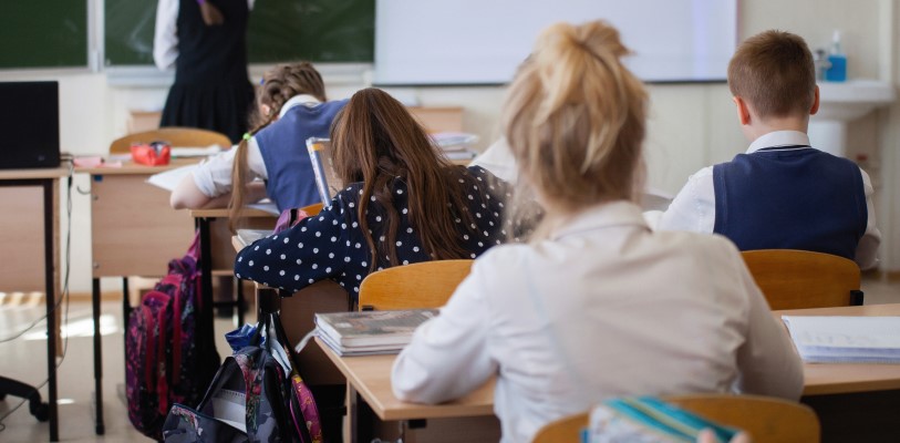 photo of middle-grade classroom from the back, looking at the teacher as though seated in the room.